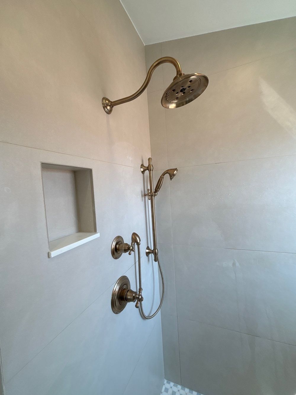 Custom tile walk-in shower with brass fixtures by H&H Signature Renovations