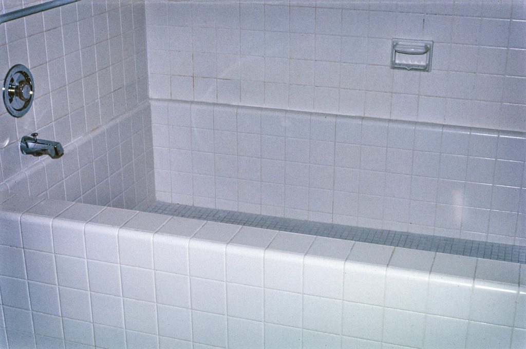 A dated bathtub and tile surround before a tub-to-shower conversion